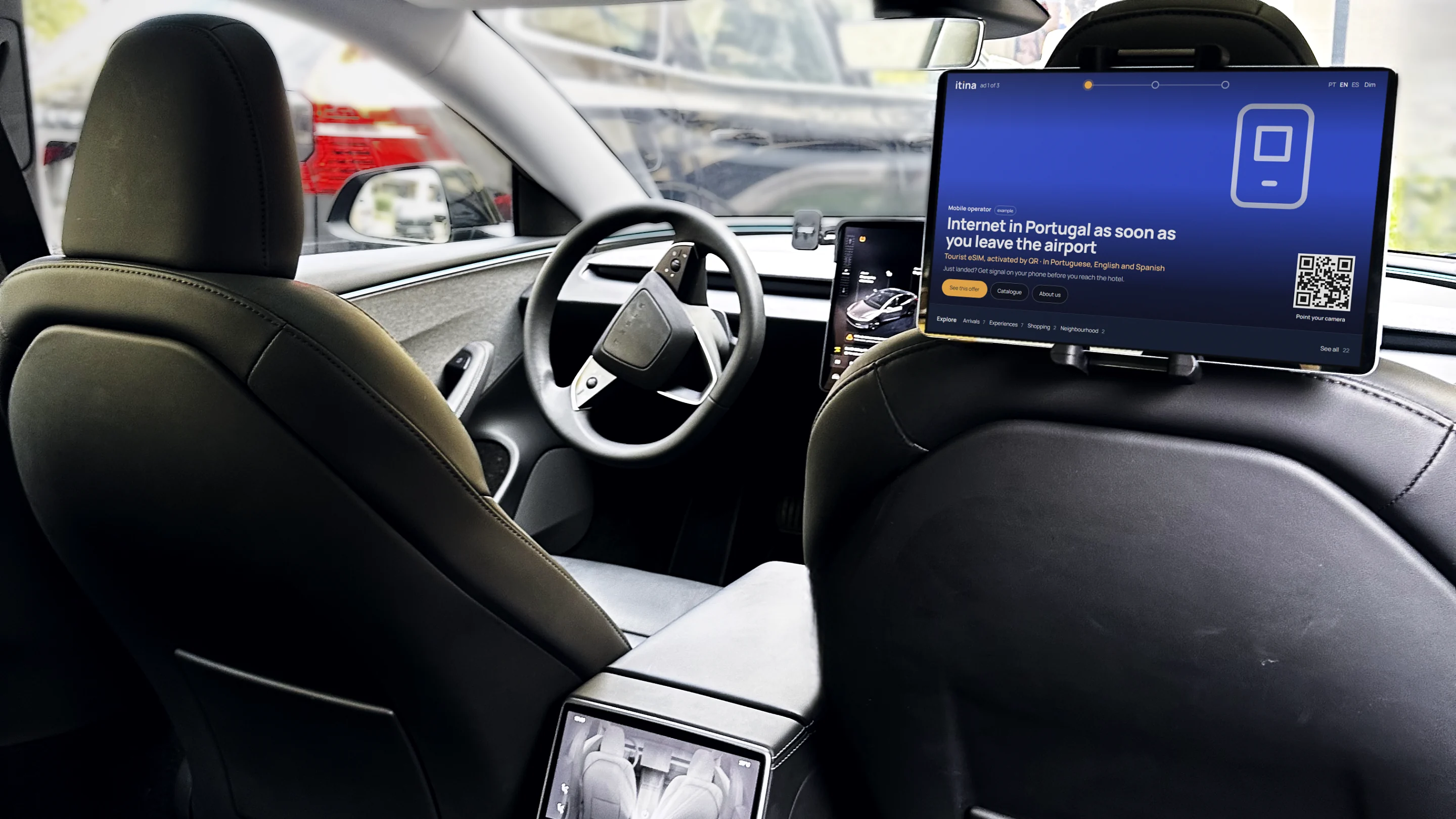 The back seat of a fleet Tesla, with the tablet on the seatback and an ad as you leave the airport